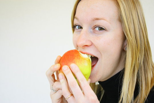 jeune fille blonde croquant une pomme