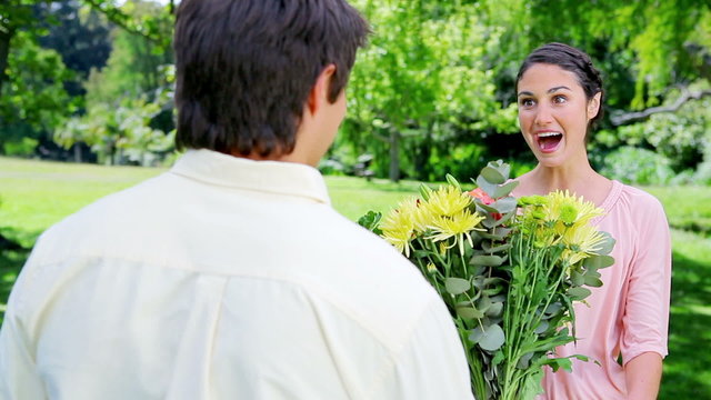Smiling brunette woman receiving a bunch of flowers