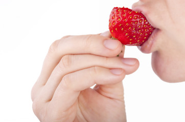 studio shot of a young woman bites into a fresh strawberry