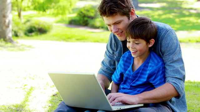 Boy on his father's tigh using a laptop