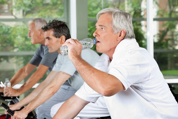 Mann im Fitnesscenter trinkt Wasser