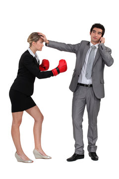 Businesswoman boxing on businessman on phone