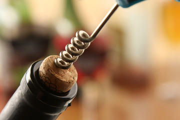 A corkscrew opening bottle of red wine
