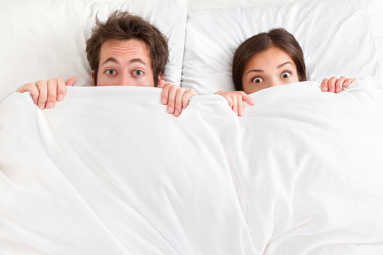Funny surprised couple in bed