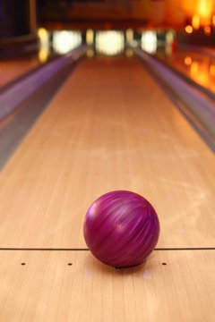 violet sphere ball standing on long bowling lane before strike
