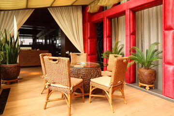 Fototapeta na wymiar Piękne wiklinowe krzesła i stolik w eleganckiej restauracji puste