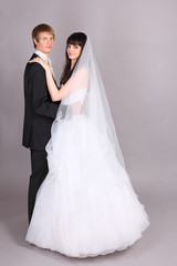 Naklejka premium Happy young groom and beautiful bride embrace and look at camera