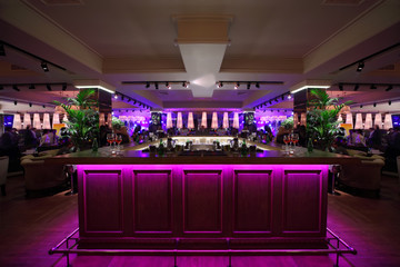 wooden bar counter with pink illumination in large restaurant