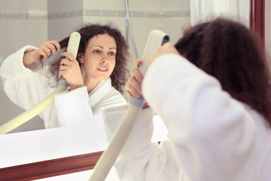 Smiling Woman Dressed In White Bathrobe Stands Near Mirror