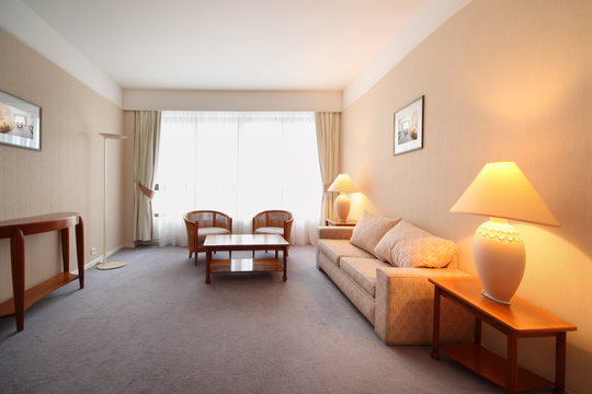 Simple light comfortable room in hotel; sofa, table and armchair