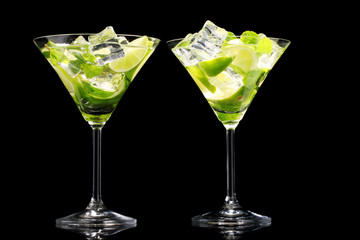 glasses of cocktails with lime and mint on black background