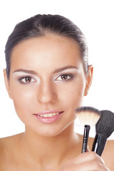 Portrait of attractive young adult woman holding brushes