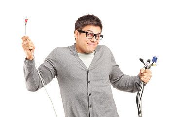 A confused male holding electronic cables