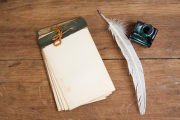 Quill ink pen and inkwell, old notepad on oak wood table