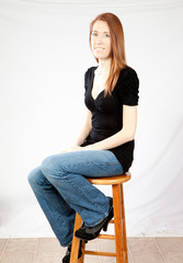 woman with  long hair sitting on a wooden stool