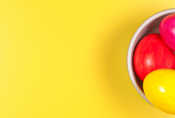 Easter eggs in bowl on yellow background.