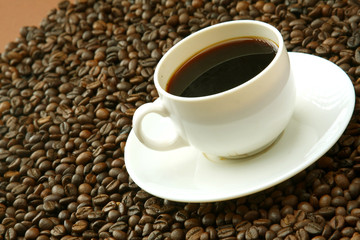 A cup of coffee on coffee beans, closeup