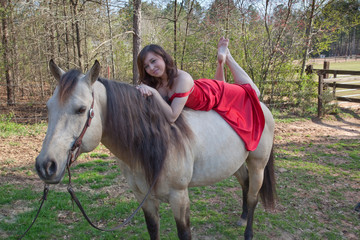 Woman in red dress riding a horse bareback