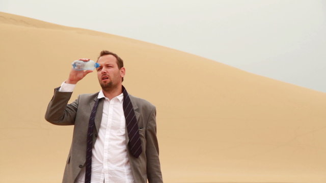 Thirsty Businessman Drinking Water From Bottle In The Desert