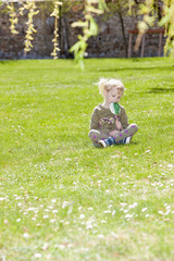 little girl with a lollipop sitting on grass