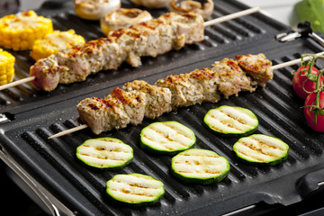 meat skewers and vegetables on electric grill