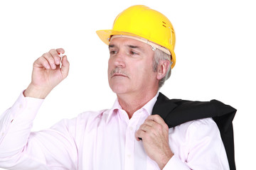 mature foreman with coat over shoulder examining pen