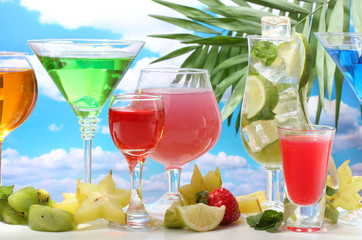 Glasses of cocktails on table on blue sky background