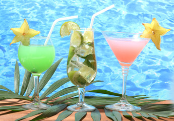 Glasses of cocktails on wooden table on blue sea background