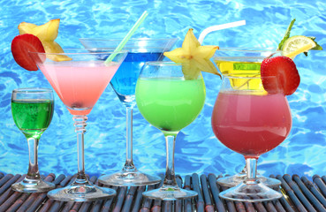 Glasses of cocktails on table on blue sea background