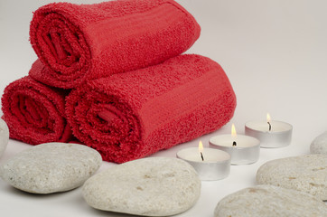 Fototapeta na wymiar Red towels with stones and candles