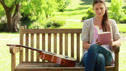 Woman sitting on a bench is reading a book - Powered by Adobe