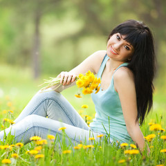Cute woman in the park with dandelions