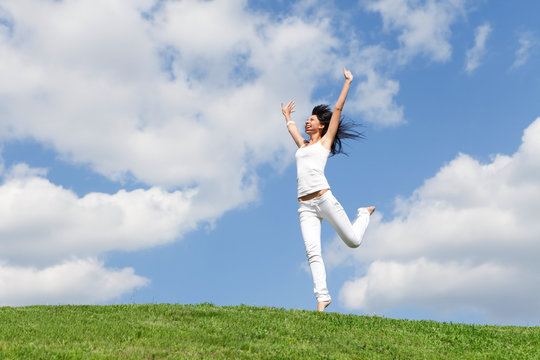 pretty young woman jumping on green grass
