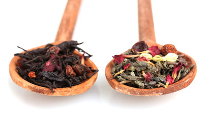 Green and black dry tea leaves in woooden spoons isolated