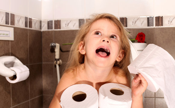 Child With A Roll Of Toilet Paper Sitting On The Toilet