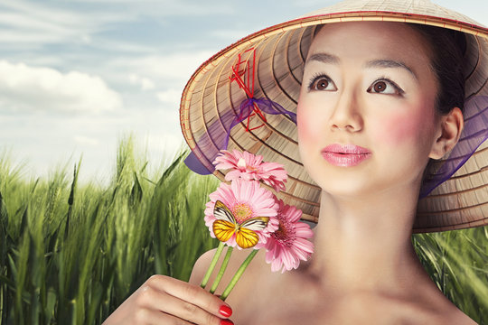 Beautiful vietnamese girl in a traditional hat is holding flower