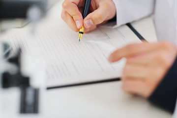 Closeup writing in document hands of medical doctor