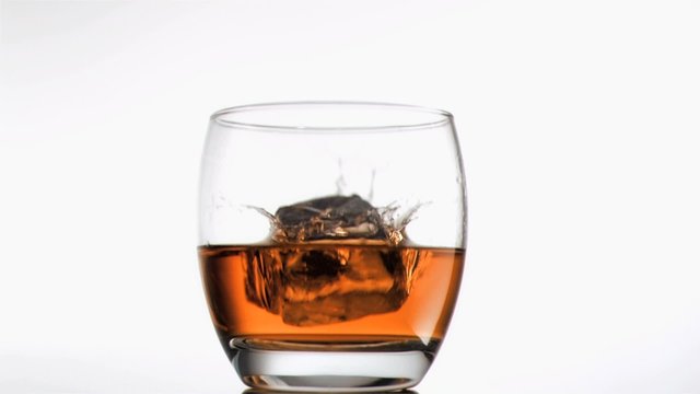 Ice cubes falling in super slow motion into a whiskey