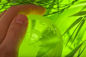 Glass earth in grass with hand