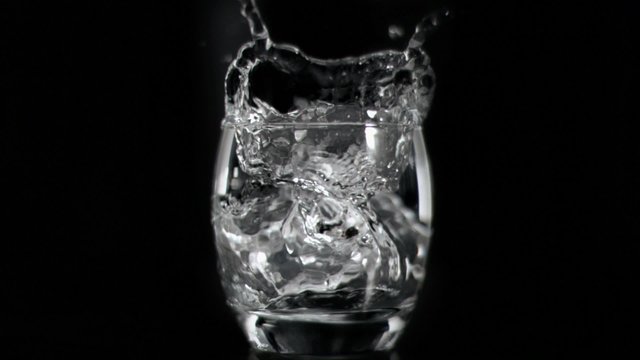 Ice cube falling in super slow motion in vodka