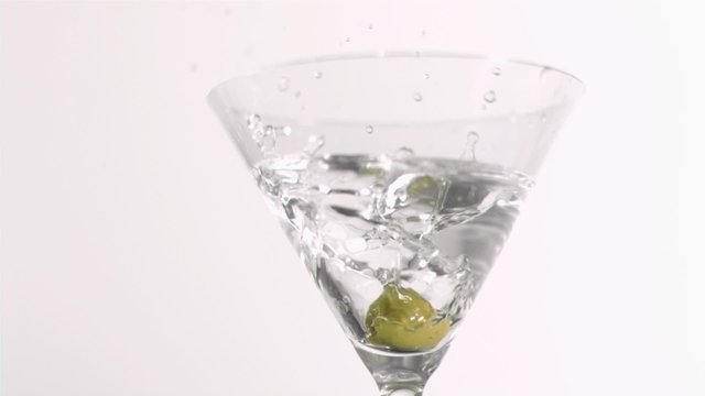 Olive falling in super slow motion in a gin