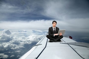 Fototapeta premium Businessman sat on the wing of an airplane