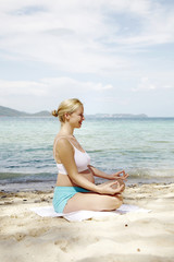 Fototapeta na wymiar junge schwangere frau macht yoga am strand