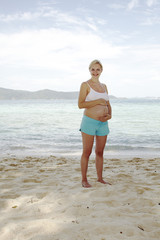 junge schwangere frau macht yoga am strand
