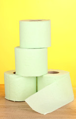 green rolls of toilet paper on wooden table on yellow