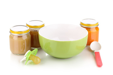 Jars of baby puree with plate and spoon isolated on white
