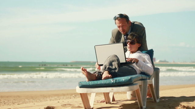Business people finishing work on laptop on the beach