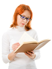 Beautiful red-haired girl in glasses reads book.