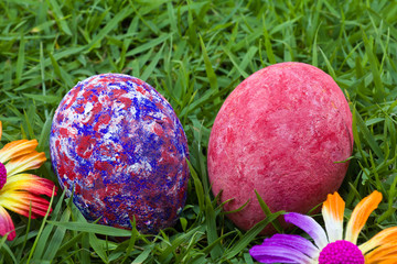 colorful painted two easter eggs on the grass with flowers