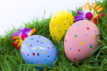 colorful painted three easter eggs on the grass with flowers